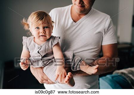 Father carrying baby daughter in arms, cropped portrait View Large Photo Image Stock Photo - Father carrying baby daughter in arms, cropped portrait. Fotosearch