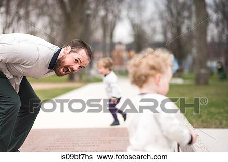 Stock Photograph - Father cheering up son in park, boy in background. Fotosearch