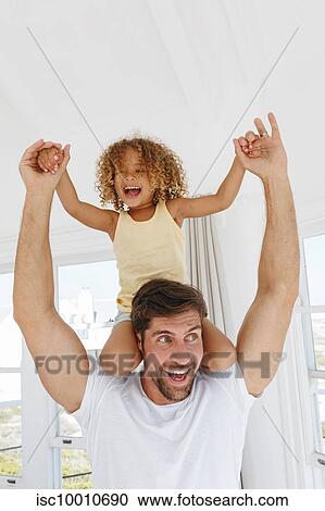 Stock Image - Father giving daughter piggyback ride in beach house. Fotosearch
