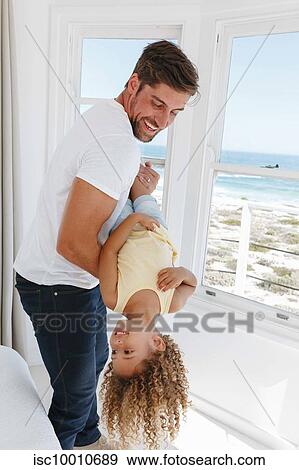 Father holding daughter upside down in beach house View Large Photo Image Stock Photo - Father holding daughter upside down in beach house. Fotosearch