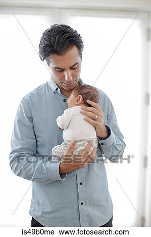 Stock Image - Father holding newborn baby boy to chest. Fotosearch