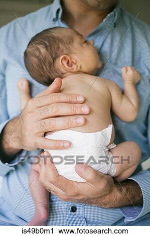 Stock Image - Father holding newborn baby boy to chest, mid section. Fotosearch