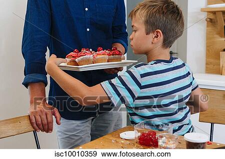 Father serving tray of cupcakes to boy at home View Large Photo Image Stock Photo - Father serving tray of cupcakes to boy at home. Fotosearch