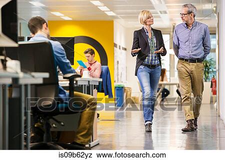 Female and male digital designers walking and talking in office View Large Photo Image Stock Photo - Female and male digital designers walking and talking in office. Fotosearch
