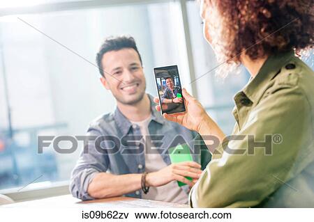 Female digital designer photographing colleague in office View Large Photo Image Stock Photo - Female digital designer photographing colleague in office. Fotosearch