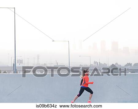 Stock Photo - Female runner running in misty morning cityscape, Melbourne, Australia. Fotosearch