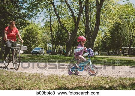 Female toddler and her grandmother cycling in park View Large Photo Image Stock Photo - Female toddler and her grandmother cycling in park. Fotosearch