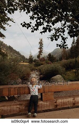 Female toddler looking out at river from rural bridge, rear view, Mineral King, California, USA View Large Photo Image Picture - Female toddler looking out at river from rural bridge, rear view, Mineral King, California, USA. Fotosearch
