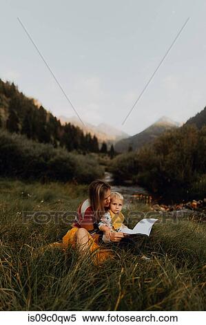 Stock Photography - Female toddler sitting on mother's lap by rural river, portrait, Mineral King, California, USA. Fotosearch
