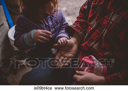 Stock Image - Female toddler with grandmother in garden looking at her hand, cropped. Fotosearch