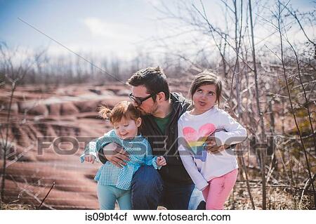 Stock Image - Female toddler with sister and father posing and pulling faces. Fotosearch