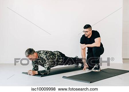 Fitness instructor observing man doing plank in studio View Large Photo Image Stock Photo - Fitness instructor observing man doing plank in studio. Fotosearch