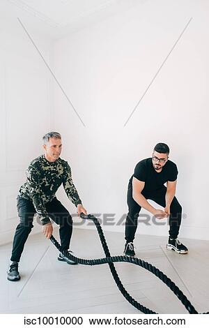 Fitness instructor observing man using battle rope in studio View Large Photo Image Stock Image - Fitness instructor observing man using battle rope in studio. Fotosearch