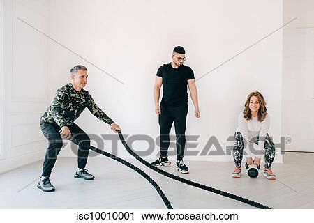 Fitness instructor observing man using battle rope in studio View Large Photo Image Stock Image - Fitness instructor observing man using battle rope in studio. Fotosearch