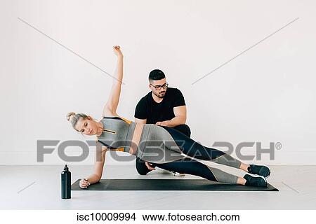 Fitness instructor observing woman doing side plank in studio View Large Photo Image Picture - Fitness instructor observing woman doing side plank in studio. Fotosearch