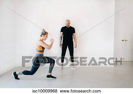 Fitness instructor observing woman doing lunges in studio View Large Photo Image Stock Photo - Fitness instructor observing woman doing lunges in studio. Fotosearch