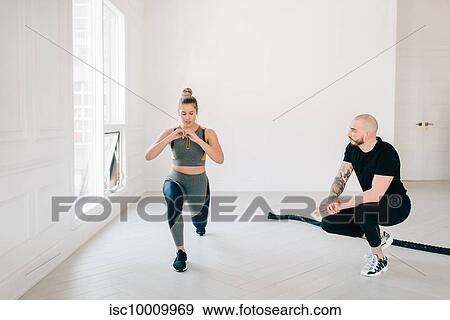 Fitness instructor observing woman doing lunges in studio View Large Photo Image Stock Photo - Fitness instructor observing woman doing lunges in studio. Fotosearch