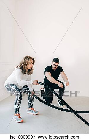 Fitness instructor observing woman using battle rope in studio View Large Photo Image Stock Photo - Fitness instructor observing woman using battle rope in studio. Fotosearch