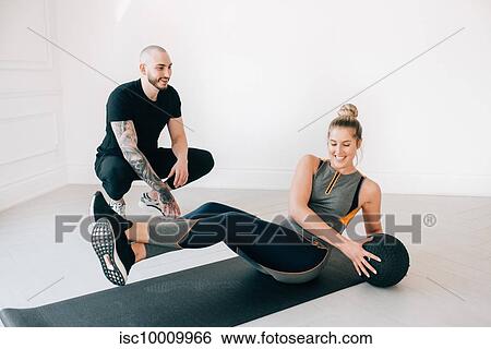 Fitness instructor observing woman doing russian twist with medicine ball in studio View Large Photo Image Stock Photograph - Fitness instructor observing woman doing russian twist with medicine ball in studio. Fotosearch