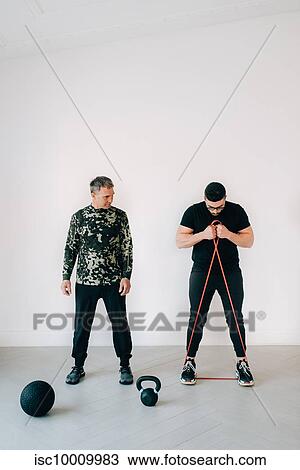 Fitness instructor teaching man using resistance band in studio View Large Photo Image Stock Image - Fitness instructor teaching man using resistance band in studio. Fotosearch