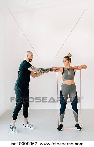 Fitness instructor teaching woman using resistance band in studio View Large Photo Image Stock Image - Fitness instructor teaching woman using resistance band in studio. Fotosearch