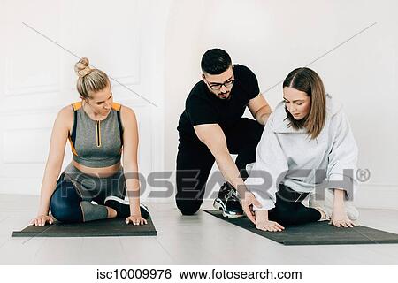 Fitness instructor teaching women stretching legs in studio View Large Photo Image Stock Photograph - Fitness instructor teaching women stretching legs in studio. Fotosearch
