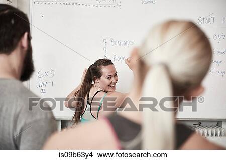 Picture - Fitness instructor writing on whiteboard in cross training gym. Fotosearch