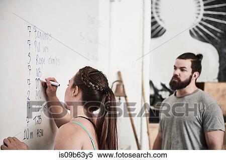 Stock Photography - Fitness instructor writing on whiteboard in cross training gym. Fotosearch