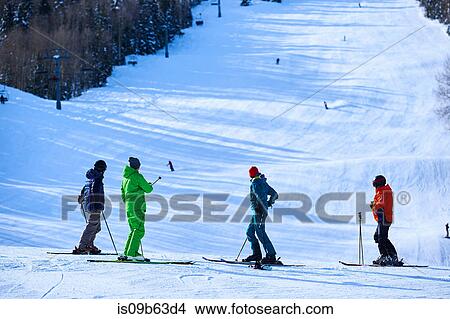 Picture - Four skiers looking out over ski slopes, Aspen, Colorado, USA. Fotosearch