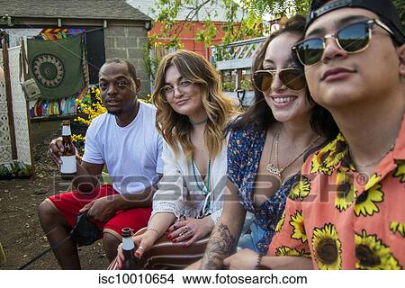 Picture - Four young adult friends relaxing at community garden party, side view portrait. Fotosearch