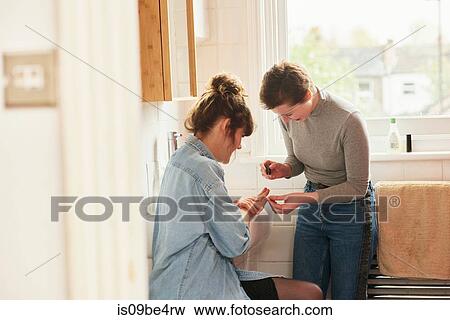 Friends applying nail varnish in bathroom View Large Photo Image Stock Photo - Friends applying nail varnish in bathroom. Fotosearch