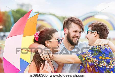Stock Image - Friends at festival arms around each other smiling. Fotosearch