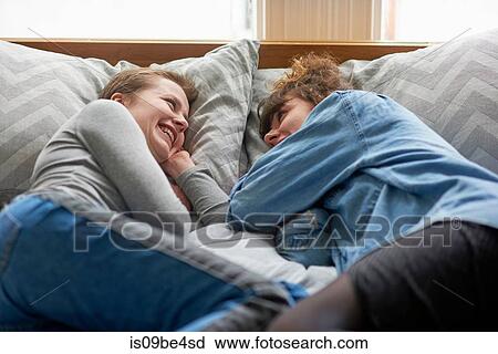 Stock Image - Friends chatting on bed. Fotosearch