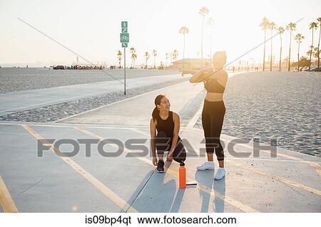 Stock Photograph - Friends doing exercises by beach, Long Beach, California, US. Fotosearch