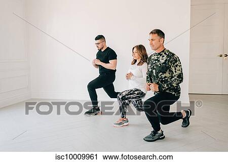 Stock Image - Friends doing lunges in studio. Fotosearch