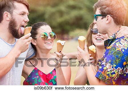 Stock Image - Friends eating ice cream cones smiling. Fotosearch