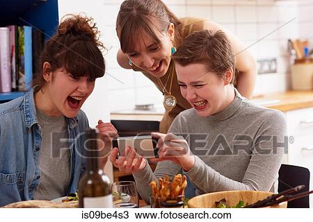 Friends laughing at something on mobile phone View Large Photo Image Stock Image - Friends laughing at something on mobile phone. Fotosearch