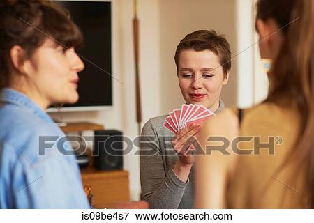 Stock Photo - Friends playing cards in living room. Fotosearch