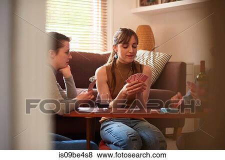 Stock Photo - Friends playing cards in living room. Fotosearch