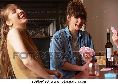 Stock Photograph - Friends playing cards in living room. Fotosearch