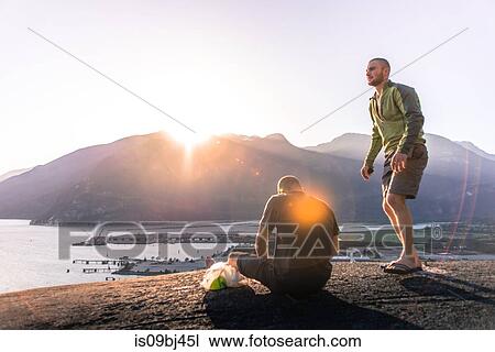Friends relaxing on mountain ledge overlooking lake, Squamish, Canada View Large Photo Image Stock Image - Friends relaxing on mountain ledge overlooking lake, Squamish, Canada. Fotosearch