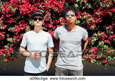 Friends standing next to each other beside red bougainvilleas View Large Photo Image Stock Photo - Friends standing next to each other beside red bougainvilleas. Fotosearch