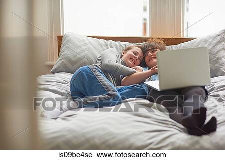 Friends using laptop on bed View Large Photo Image Stock Image - Friends using laptop on bed. Fotosearch