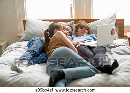 Friends using laptop on bed View Large Photo Image Stock Image - Friends using laptop on bed. Fotosearch