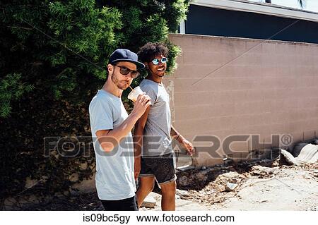 Friends walking down dirt track by wall View Large Photo Image Stock Photo - Friends walking down dirt track by wall. Fotosearch