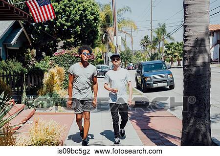 Stock Photo - Friends walking down sunny street, Long Beach, California, US. Fotosearch