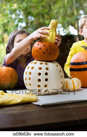 Girl and brother stacking carved pumpkins on garden table View Large Photo Image Stock Photo - Girl and brother stacking carved pumpkins on garden table. Fotosearch
