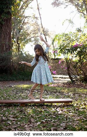 Girl balancing on wooden step in shaded garden View Large Photo Image Stock Photograph - Girl balancing on wooden step in shaded garden. Fotosearch