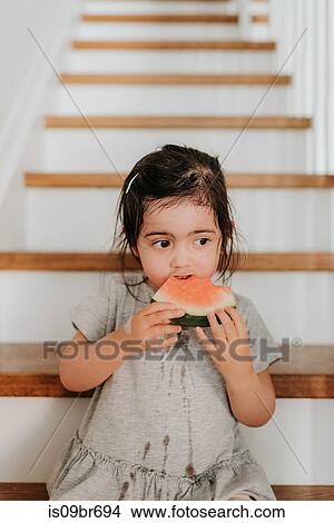 Picture - Girl enjoying watermelon on stairs. Fotosearch