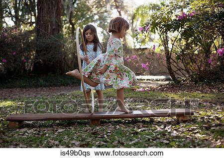 Stock Photograph - Girl holding plastic hoop, sister running through. Fotosearch